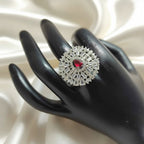 Shangri American Diamond floral halo ring with a red pear-cut center stone on a black display hand