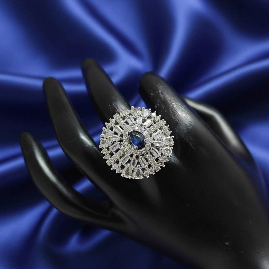 Shangri American Diamond floral halo ring with a blue pear-cut center stone and baguette accents on a black hand model