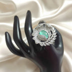 Shangri floral American Diamond ring with a mint green centre stone and adjustable band on a black display hand