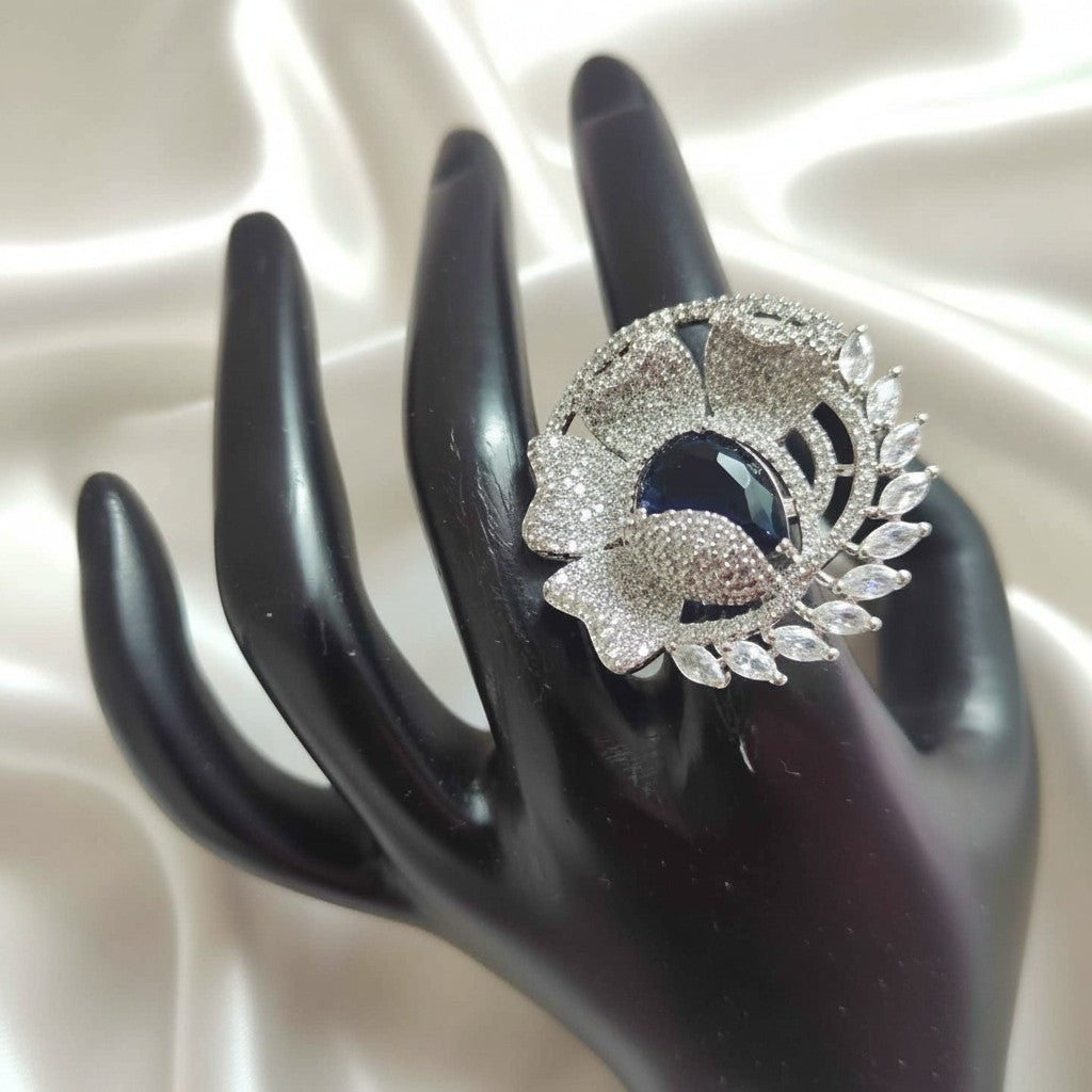 Shangri floral adjustable ring featuring sparkling American Diamond stones and a deep blue teardrop centre stone