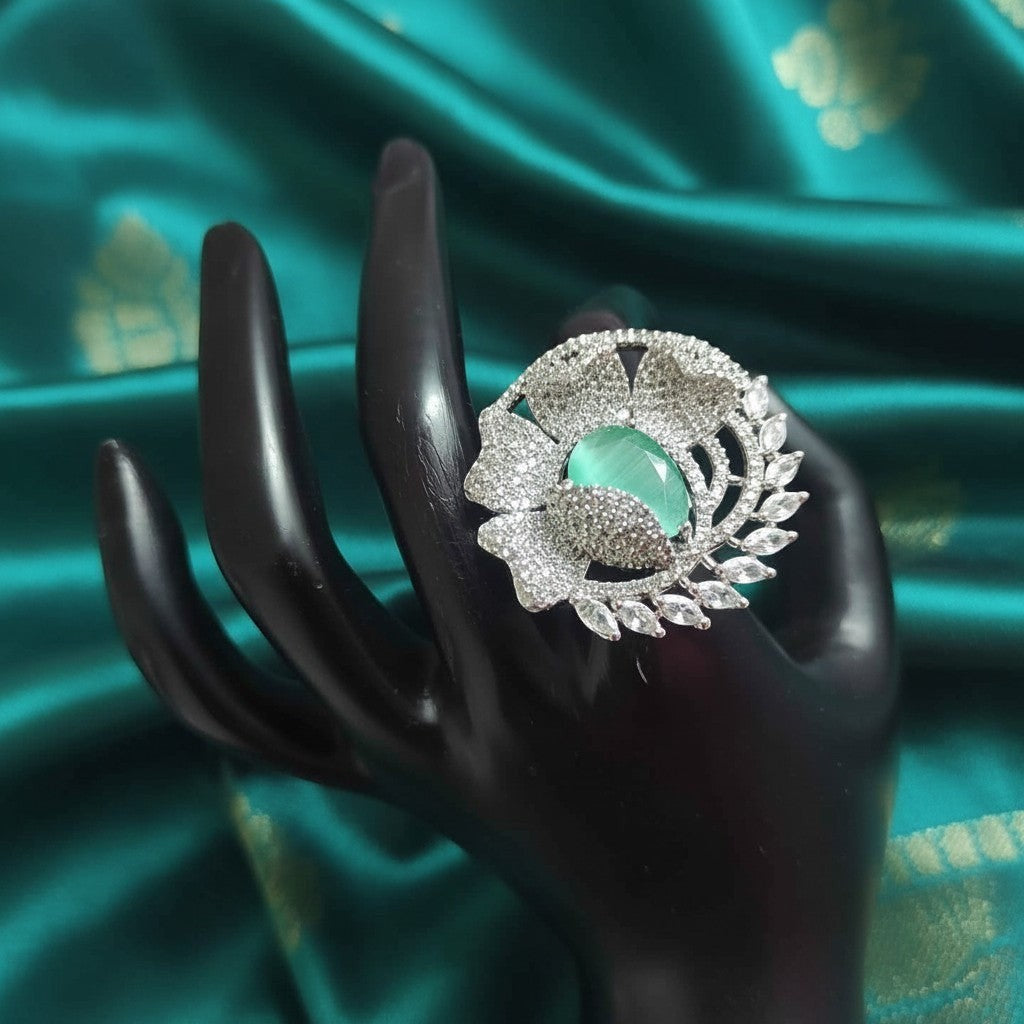 Shangri floral American Diamond ring featuring a mint green centre stone on a black display hand against silk fabric
