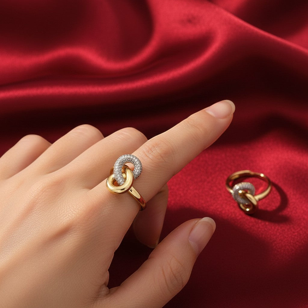 Shangri gold-plated cocktail ring with intertwined loops and sparkling Austrian stones on a red satin background