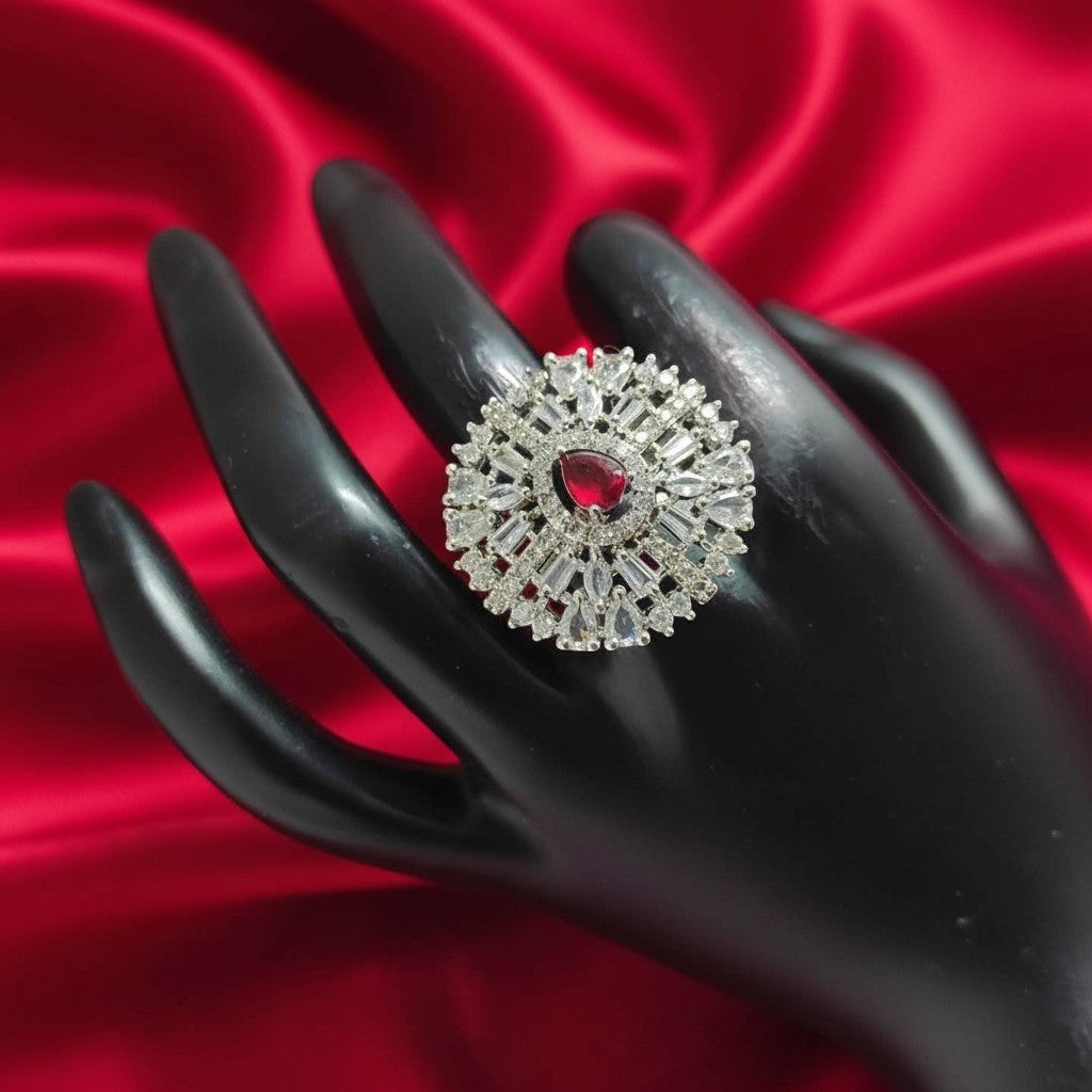 Shangri American Diamond floral halo ring with a red pear-cut center stone on a black display hand against red silk.